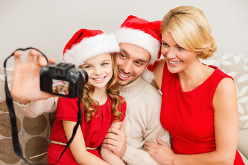 Image showing smiling family in santa helper hats taking picture