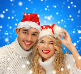 Image showing smiling couple in sweaters and santa helper hats