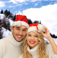 Image showing smiling couple in sweaters and santa helper hats