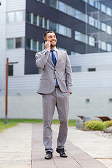 Image showing smiling businessman with smartphone outdoors