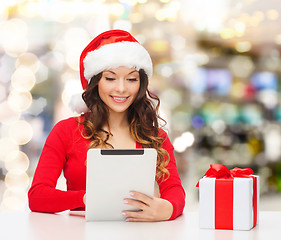 Image showing smiling woman in santa hat with gift and tablet pc