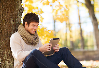 Image showing smiling young man with tablet pc in autumn park