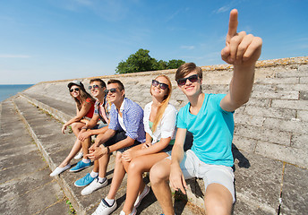 Image showing group of smiling friends sitting on city street