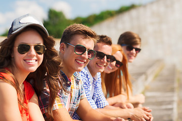 Image showing close up of smiling friends sitting on city street