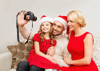 Image showing smiling family in santa helper hats taking picture