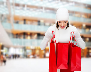 Image showing smiling young woman with red shopping bags