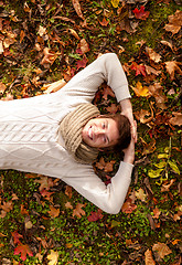 Image showing smiling young man lying on ground in autumn park