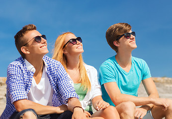 Image showing group of smiling friends sitting on city street