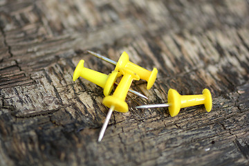 Image showing yellow push pins on old wooden background