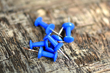 Image showing blue push pins on old wooden background