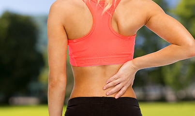 Image showing close up of sporty woman touching her back