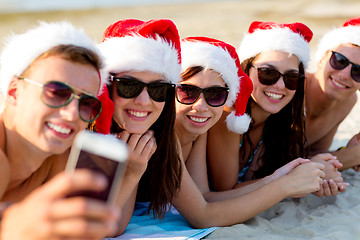 Image showing group of friends in santa hats with smartphone