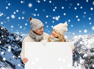 Image showing smiling couple in winter clothes with white board