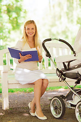 Image showing happy mother with book and stroller in park