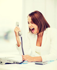 Image showing woman shouting into phone in office