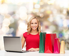 Image showing smiling woman in red shirt with gifts and laptop