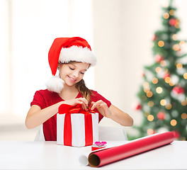 Image showing smiling girl in santa helper hat with gift box