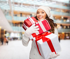 Image showing smiling young woman in santa helper hat with gifts