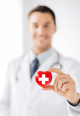 Image showing male doctor holding heart with red cross symbol