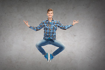 Image showing smiling young man jumping in air