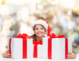 Image showing smiling girl in santa helper hat with gift boxes