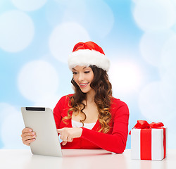 Image showing smiling woman in santa hat with gift and tablet pc