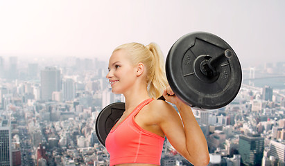 Image showing smiling sporty woman exercising with barbell