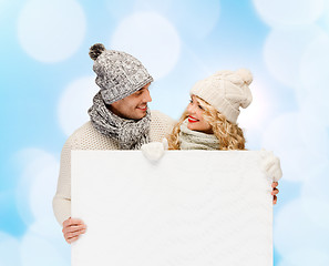Image showing smiling couple in winter clothes with white board