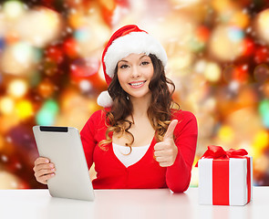 Image showing smiling woman in santa hat with gift and tablet pc