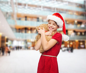 Image showing smiling girl in santa helper hat with teddy bear