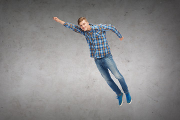 Image showing smiling young man jumping in air