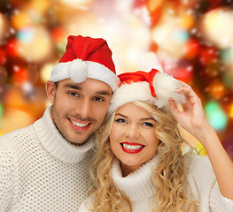 Image showing smiling couple in sweaters and santa helper hats