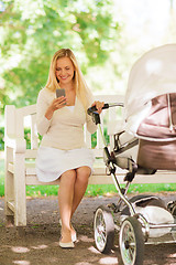 Image showing happy mother with smartphone and stroller in park