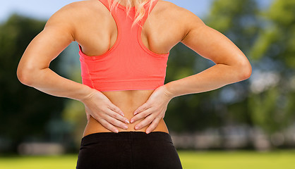 Image showing close up of sporty woman touching her back