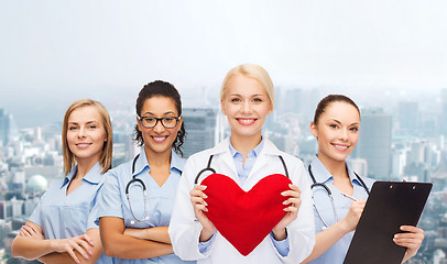 Image showing smiling female doctor and nurses with red heart