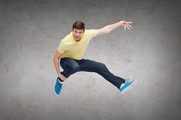 Image showing smiling young man jumping in air