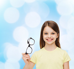 Image showing smiling cute little girl holding black eyeglasses