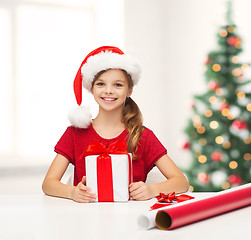 Image showing smiling girl in santa helper hat with gift box