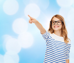 Image showing cute little girl in eyeglasses pointing in the air