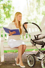 Image showing happy mother with book and stroller in park