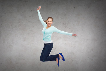 Image showing smiling young woman jumping in air