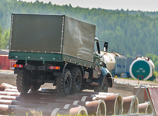 Image showing Curtain sided truck moves on obstacle from pipes