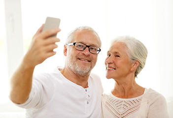 Image showing happy senior couple with smartphone at home