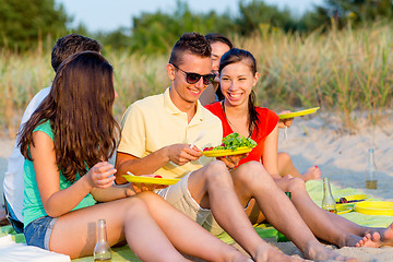 Image showing smiling friends sitting on summer beach