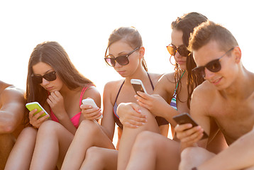 Image showing friends with smartphones on beach