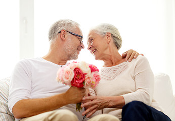 Image showing happy senior couple with bunch of flowers at home