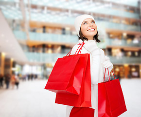 Image showing smiling young woman with red shopping bags