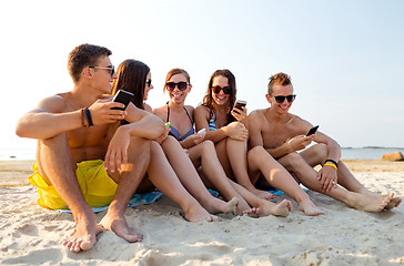 Image showing friends with smartphones on beach