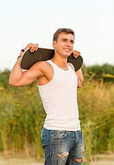 Image showing smiling teenage boy with skateboard outdoors