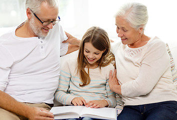 Image showing smiling family with book at home